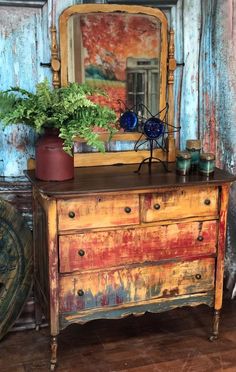 an old dresser with a mirror and potted plants on top