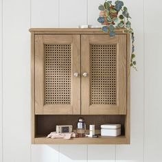 a wooden cabinet sitting on top of a white wall next to a shelf filled with items