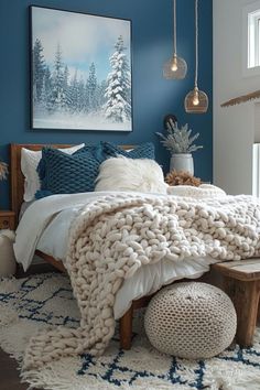 a bedroom decorated in blue and white with a large bed covered in blankets, pillows and throws