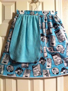 a blue and white skirt with pictures on it hanging from a hook in front of a door