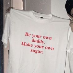 a man holding up a t - shirt that says be your own daddy make your own sugar