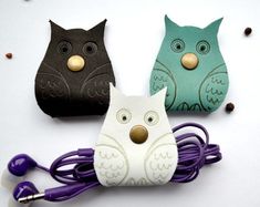 three owls with ear buds are sitting next to each other on a white surface, surrounded by coffee beans