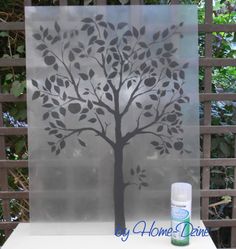 a spray painted tree on a glass block with a fence in the backround