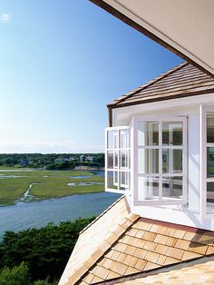 an open window on the side of a building overlooking a body of water and trees