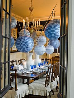 a dining room table with blue and white balls hanging from it's centerpiece