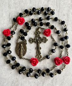 A beautiful handcrafted Catholic five decade chain style prayer rosary. It's a great and thoughtful gift for someone special. Made with black 6mm crystal beads for the decades, red rose accent 8mm beads for the Our Father's and bronze Crucifix and Virgin Mary medallion. Tampa is know for our rich history founded by the Spaniards and Italians. Every year our city is taken over by pirates for the Gasparilla Parade. This rosary is inspired by the Spanish pirates that once called our city home.  Eac Vintage Black Rosary Gift, Vintage Black Rosary As Gift, Black Cross Rosary As Gift, Vintage Black Rosary As A Gift, Black Beads Cross Rosary Gift, Black Crucifix Rosary As Gift, Black Crucifix Rosary Bracelet As Gift, Handmade Black Rosary Gift, Crucifix Jewelry With Black Beads As Gift