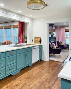 a kitchen with blue cabinets and white counter tops next to an open living room door