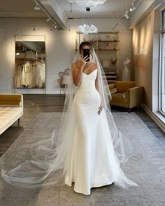 a woman in a white wedding dress is taking a selfie with her cell phone