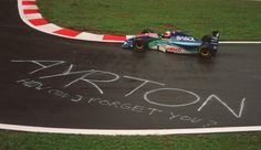 a man driving a racing car down a race track with graffiti written on the side