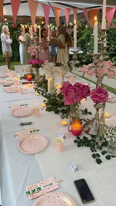 the table is set up with pink flowers and candles for an outdoor wedding reception or social gathering