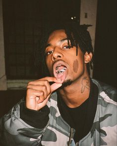 a young man with dreadlocks is making a funny face while brushing his teeth