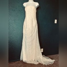 a white wedding dress is on display in front of a green wall and carpeted floor