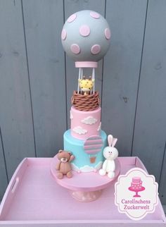 a pink and blue cake sitting on top of a wooden table next to a stuffed animal