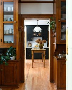 an open door leading to a kitchen with black cabinets and wood flooring on the walls