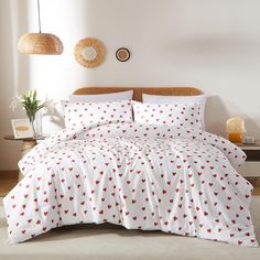 a bed with red hearts on it in a room next to a table and lamp