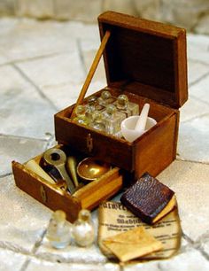 an open wooden box filled with bottles and other items on a tile floor next to a pair of scissors