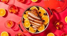 an overhead view of orange slices and sliced meat in a bowl on a red surface