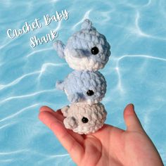 two tiny crocheted baby sheeps sitting on top of each other in the water