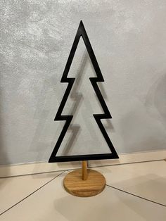 a small wooden christmas tree sitting on top of a white floor next to a wall