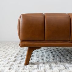 a brown leather bench sitting on top of a rug