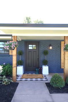 the front entrance to a house with flowers and potted plants on either side of the door