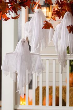 halloween decorations hanging from the ceiling in front of a porch with pumpkins and leaves