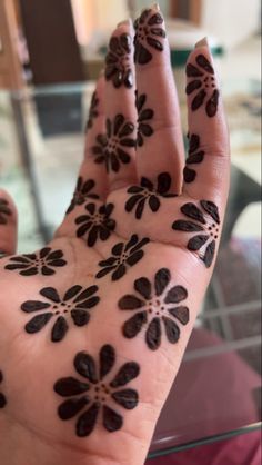 a person's hand with black hendix on it and flowers painted on the palm