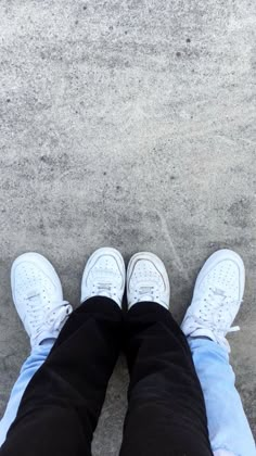 two people standing next to each other with their feet up in the air and one person wearing white sneakers