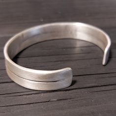 Solid Sterling Silver cuff bracelet. Brushed matte finish. Strong and adjustable. Cuff Measurement : Width : approx. 12 mm(0.5 inch). Thickness : about 1.5 mm Cuff in pics - Length, end to end, without the gap : approx. 16 cm Cuff size : Sizes are measured from end to end of the cuff, so if you measure your wrist circumference, cuff size would be about 1.5-2 cm less, for example, if your your wrist circumference is about 16.5 cm, choose 15 cm, but, if you like it with a bigger gap and loose style as the model in pics choose 2-3 cm less then your wrist. If your wrist circumference falls in between two sizes, go up a size as you can always adjust the cuff bracelet to have a tighter fit around your wrist, if you like it tight, go down a size. S - 14 cm / 5.5 Inches M - 15 cm / 5.9 Inches L - Mens Silver Cuff Bracelet, Masculine Jewelry, Mens Bangles, Jewelry Design Studio, Modern Silver Jewelry, Finish Strong, Sterling Silver Bangle Bracelets, Sterling Silver Cuff Bracelet, Silver Bangle Bracelets