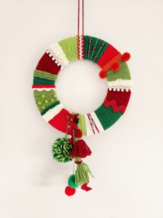 a christmas wreath hanging on the wall with pom - poms and other decorations