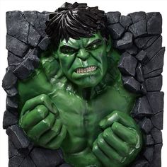 a statue of the incredible hulk is shown in front of a stone wall with green paint