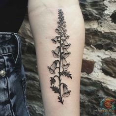 a black and white flower tattoo on the right arm, with leaves growing out of it