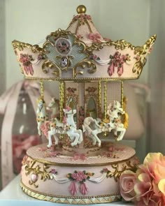 there is a pink and gold carousel with horses on the top, next to flowers