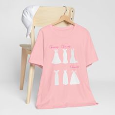 This t shirt is a must-have for any bride or bridesmaid who loves wedding dresses. It features a chic design of elegant outlines of dresses in different styles. It's a perfect way to express your style and your excitement for the big day.  You can wear this t shirt for any pre-wedding event, such as wedding dress shopping, bridal showers, hen parties, or just hanging out with the bride squad. It's also a wonderful gift idea for the bride or her besties.  This t shirt is made from soft and comfor Wedding Engagement Gifts, Bride Squad, Dress Shopping, Shopping Day, Wedding Dress Shopping, Fashion Logo, Bridal Showers, Wedding Event, Gift Wedding