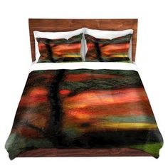 a bed covered in a colorful comforter with pillows and pillow covers on top of it