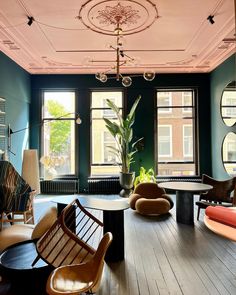 a living room filled with lots of furniture next to large windows and potted plants