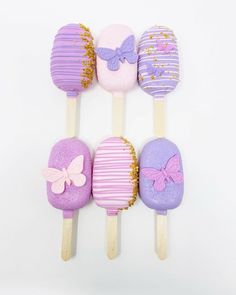 four different colored lollipops on sticks with bows and gold flecks