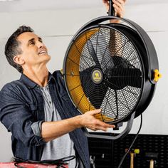 a man is holding a large fan in his hand while he looks up at the ceiling