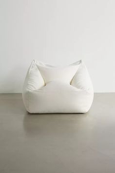 a large white bean bag chair sitting on top of a cement floor next to a wall