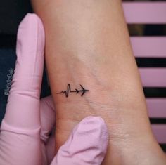 a small heartbeat tattoo on the wrist with an arrow pointing up at it's center