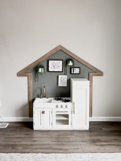 a kitchen with white cabinets and pictures on the wall