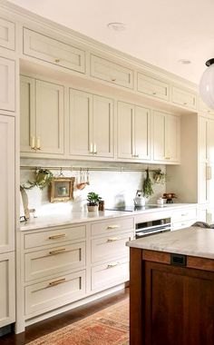 a kitchen with lots of white cabinets and wood flooring on the counter top, along with an island in front of it