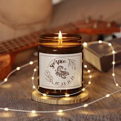 a candle that is sitting on a table next to some string lights and a guitar