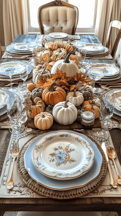 a dining room table is set with plates, silverware and pumpkins on it