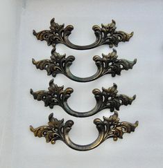 three ornate metal handles on a white surface