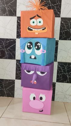 four colorful boxes with faces on them in front of a checkered wall