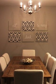 a dining room table with four pictures on the wall above it and a chandelier