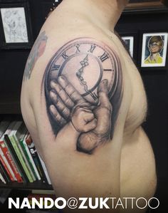 a man's arm with a clock tattoo on it and his hand holding the clock