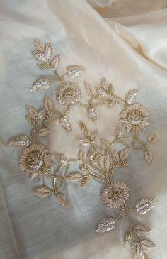 an embroidered white fabric with gold leaves on the top and bottom, as well as other material