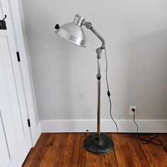 a floor lamp sitting on top of a hard wood floor next to a white door